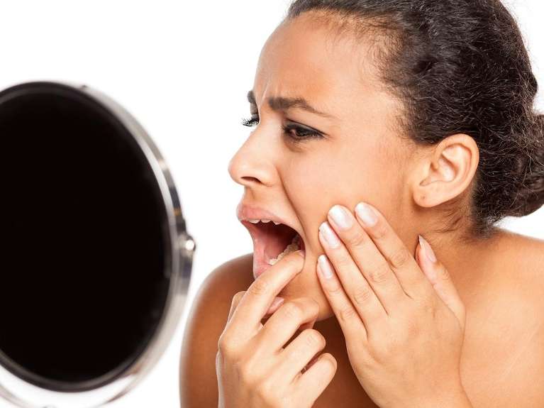 Woman checking her teeth in the mirror in Troy