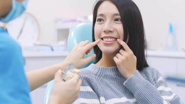 Smiling woman at a dental clinic while a dentist examines her teeth.