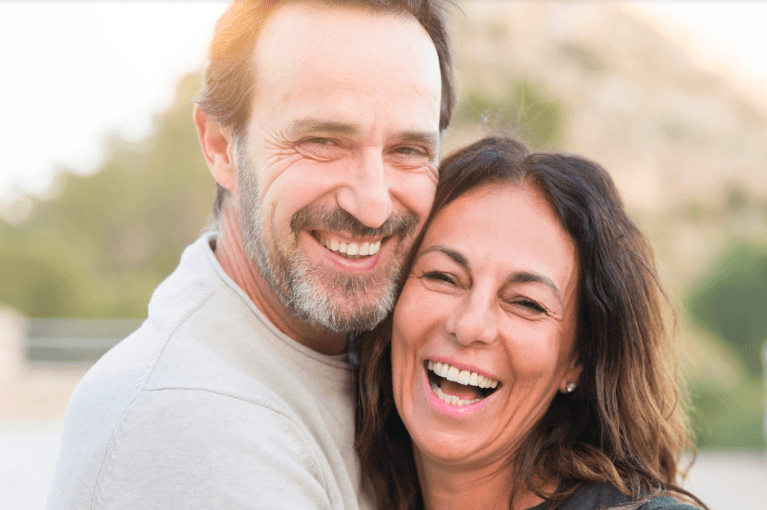 couple smiling with front teeth dental crowns