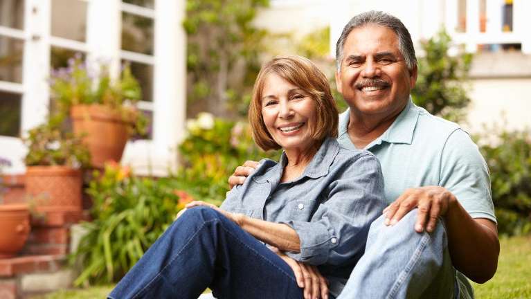 A cheerful, smiling couple with perfect dentures in their backyard