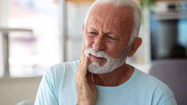 Old man in Troy NY holding his swelled right cheek