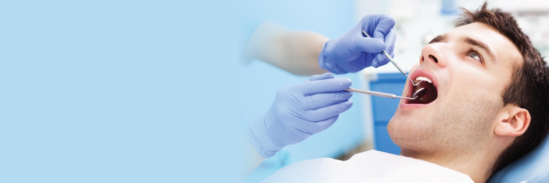 man sitting in dental chair getting gums checked